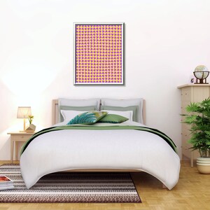 May include: A white bed with a green and white patterned throw pillow and a framed print of a yellow and purple geometric pattern. The bed is in a bedroom with a wooden nightstand, a potted plant, and a wooden dresser with a globe on top.