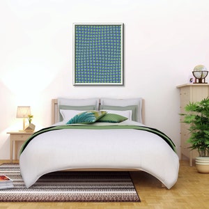 May include: A white bed with a green and white patterned throw blanket and two green pillows. A framed print with a blue and green pattern hangs above the bed. A wooden nightstand with a lamp and a small plant sits next to the bed. A wooden dresser with a globe and a plant sits on the right side of the image.