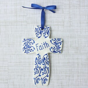 May include: A handmade wooden sign with the text "Welcome" in a handwritten style. The sign is painted white with a distressed finish and features a decorative floral design in shades of pink and green. It is designed for indoor or outdoor use.