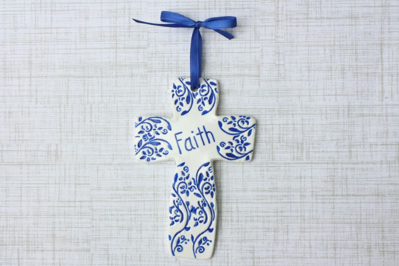 May include: A handmade wooden sign with the text "Welcome" in a handwritten style. The sign is painted white with a distressed finish and features a decorative floral design in shades of pink and green. It is designed for indoor or outdoor use.