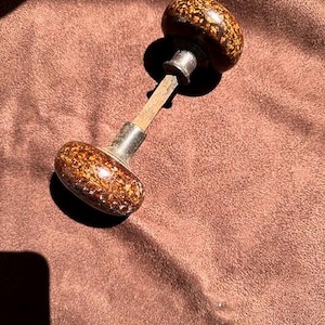 May include: A brown and gold ceramic door knob with a metal spindle.