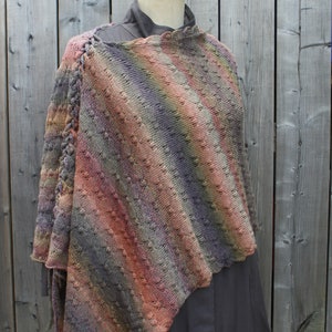 May include: A multi-colored knitted shawl with a diagonal striped pattern. The shawl is draped over a dress form and has a fringe on the bottom edge.