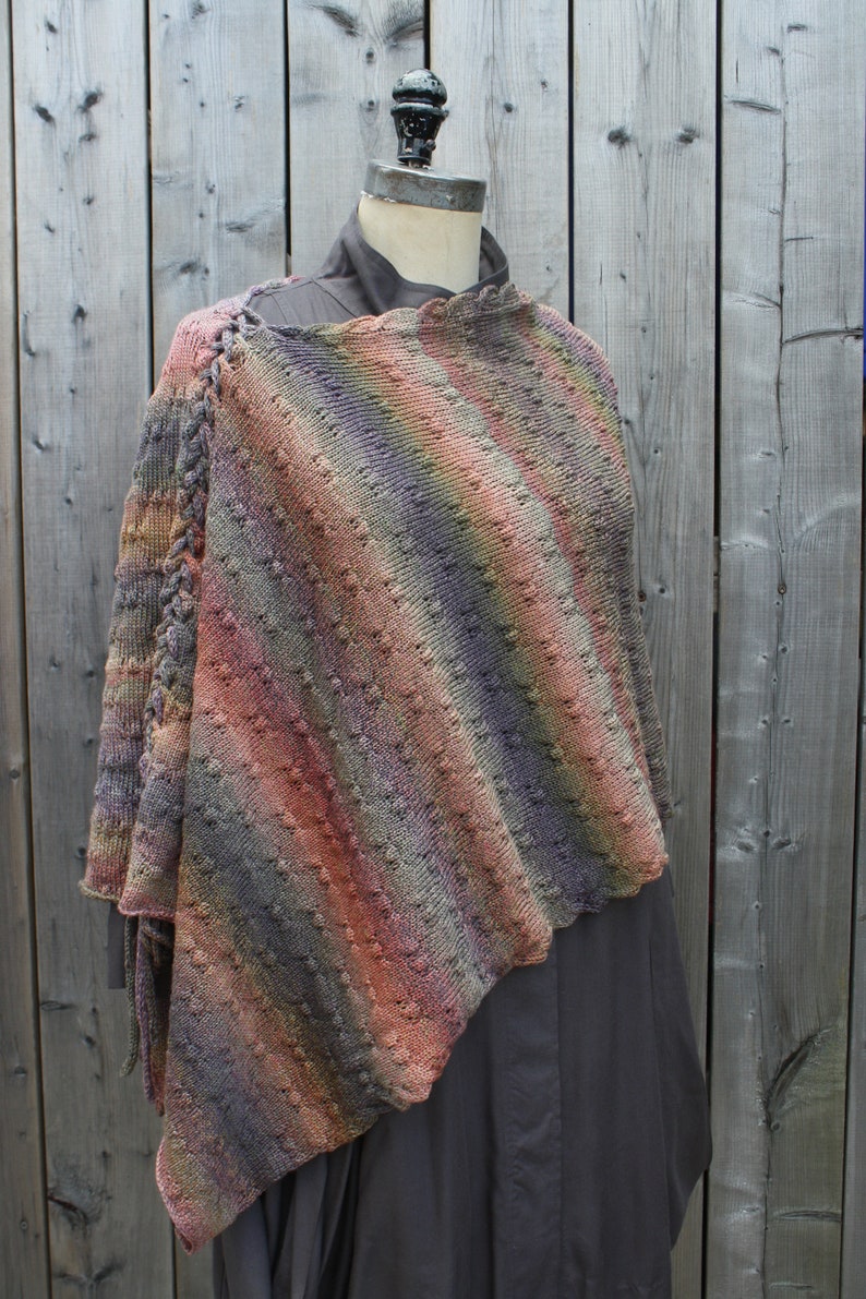 May include: A multi-colored knitted shawl with a diagonal striped pattern. The shawl is draped over a dress form and has a fringe on the bottom edge.