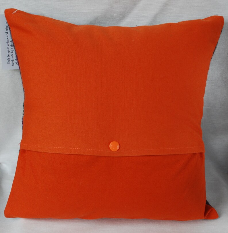May include: Orange pillow with a hidden zipper closure and a button on the back. The pillow is made of a soft, comfortable fabric.