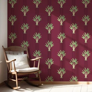 May include: Deep red wallpaper featuring a repeating design of green, palm-like plants. Dark vertical stripes separate the plant motifs. A wooden rocking chair with a white cushion is in front of the wall.