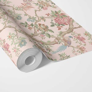 May include: A roll of wallpaper featuring a floral design with pink, green, and blue accents. The pattern includes flowers, birds, and branches on a light pink background. The wallpaper is unrolled, revealing the intricate details of the design.