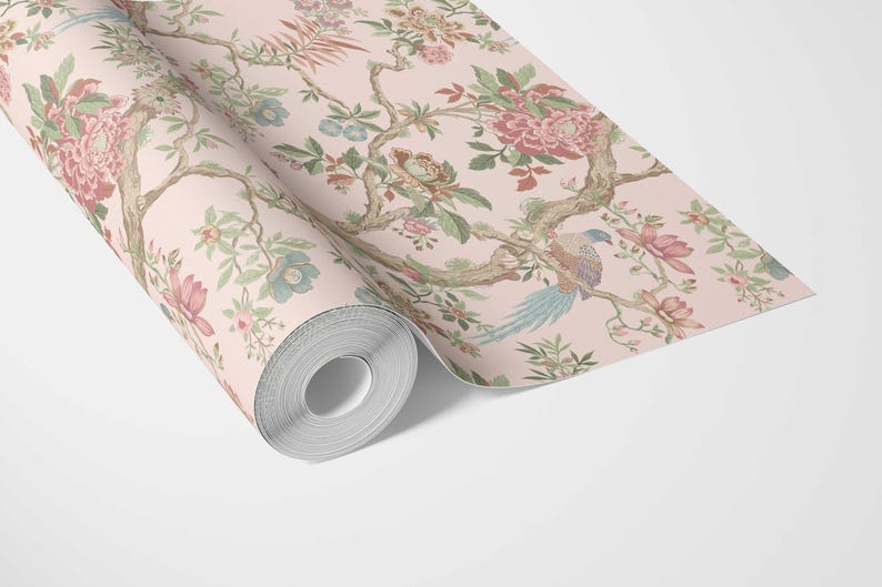 May include: A roll of wallpaper featuring a floral design with pink, green, and blue accents. The pattern includes flowers, birds, and branches on a light pink background. The wallpaper is unrolled, revealing the intricate details of the design.