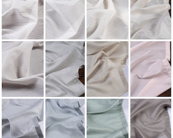 Könnte beinhalten: Eine Sammlung von 10 Stoffmustern in verschiedenen Farben und Texturen, darunter Weiß, Beige, Rosa, Grau, Hellblau, Grün und Braun. Der Stoff hat eine subtile, gewebte Textur.