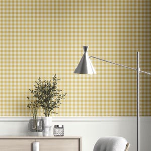 May include: A room featuring yellow and white gingham wallpaper. A silver lamp with a conical shade is on the right. A wooden cabinet displays vases and a small jar. A white wall and a chair are also visible.