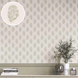 Könnte beinhalten: Cremefarbene Tapete mit einem sich wiederholenden Muster aus stilisierten floralen Motiven in einem gedämpften Grünton. Eine Nahaufnahme zeigt das florale Detail. Die Tapete befindet sich an einer Wand mit Zierleiste und einem Regal mit Büchern und Vasen.
