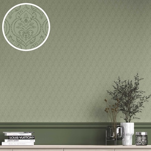 Op de afbeelding: Saliegroen behang met een subtiel textuurpatroon. Een cirkelvormige inzet toont een gedetailleerd damastontwerp. Het onderste gedeelte heeft een donkergroene rand en een witte plank met decoratieve items.