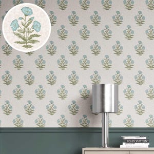 May include: Wallpaper with a repeating pattern of blue flowers and green leaves on a cream backdrop. A close-up shows the flower design. A silver lamp and books are on a wooden surface.