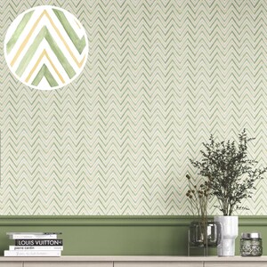 Może przedstawiać: Tapeta w jasnozielone i kremowe zygzaki. Zbliżenie pokazuje akwarelowy wzór z zielonymi i żółtymi akcentami. Tapeta jest prezentowana z zieloną ścianą akcentującą, książkami i dekoracyjnymi roślinami.