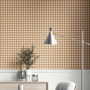 May include: A room featuring tan and white gingham wallpaper. A silver lamp with a conical shade is positioned to the right. A white cabinet holds decorative vases and a small glass jar. The room has a neutral colour palette.