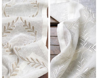May include: White sheer table runner with a delicate embroidered leaf design in a light brown color. The runner is made of a soft, lightweight fabric and has a subtle sheen.