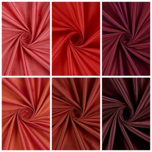 May include: Six swatches of silk fabric in various shades of red, from light pink to deep burgundy. The fabric is arranged in a spiral pattern, showcasing its smooth texture and luxurious drape.