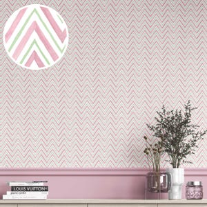 May include: Pink and white chevron patterned wallpaper. A close-up shows a watercolor detail of pink and green chevron stripes. The wallpaper covers the wall, with a pink border and a shelf with books and decorative items.