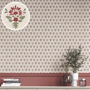 May include: Cream-colored wallpaper with a repeating pattern of small, red floral motifs. A circular inset shows a larger floral design in red and green. The wall is decorated with a dark red baseboard and a shelf with books and decorative items.