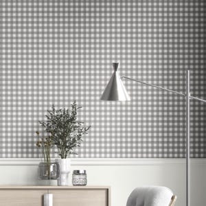 Pode incluir: Um quarto com papel de parede xadrez cinza e branco. Um armário de madeira exibe um vaso com vegetação, um frasco de vidro e um vaso transparente com flores secas. Uma lâmpada prateada com uma sombra cônica está à direita.