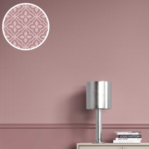 May include: A close-up of a wall with a repeating pattern in a dusty rose color. A circular inset shows a floral design. A silver lamp sits on a light-colored cabinet, with books stacked below.