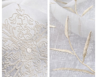May include: Close-up of two white sheer curtains with embroidered designs. One curtain features a large, intricate floral pattern, while the other has a simple, repeating leaf design. Both designs are in a light beige color.