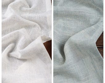 Könnte beinhalten: Zwei Stoffstücke, eines weiß und eines hellblau, werden in einer Nahaufnahme gezeigt. Der Stoff hat eine gewebte Textur und ist leicht zerknittert.