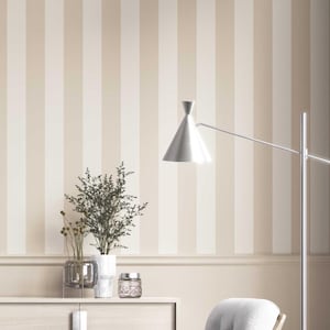May include: A room with vertical striped wallpaper in shades of beige and cream. A silver lamp with a conical shade extends from the right. A white cabinet holds decorative vases and a small jar with a lid.