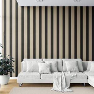 May include: A modern living room featuring a white sectional sofa with several white pillows and a white throw blanket. The wall behind the sofa is decorated with vertical black and beige stripes. A potted plant sits to the left of the sofa.