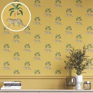 May include: Mustard yellow wallpaper featuring a repeating pattern of leopards and palm trees. A circular inset shows a leopard walking near a palm tree. The wallpaper has a textured appearance and is suitable for interior design.