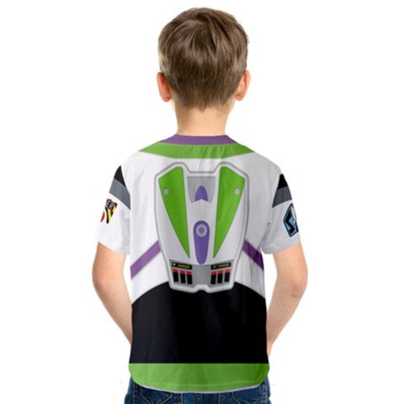 May include: A white, green, and purple t-shirt with a printed image of Buzz Lightyear's space ranger suit on the back. The shirt has short sleeves and a crew neck.