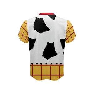 Puede incluir: Una camisa blanca de manga corta con un patr&oacute;n de vaca blanco y negro en la parte delantera y un patr&oacute;n de cuadros amarillo y rojo en las mangas y la parte inferior.