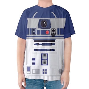 May include: A blue and white graphic t-shirt depicting the Star Wars character R2-D2. The shirt has a blue collar and sleeves, with the droid's details printed on the front. The design includes panels, lights, and mechanical elements.