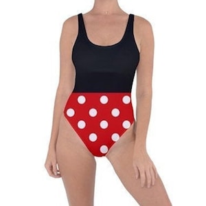 May include: A black and red polka dot swimsuit. The top is black, and the bottom is red with white polka dots. The swimsuit has a scoop neckline and tank straps.
