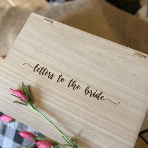 Puede incluir: Una caja de madera con tapa con bisagras, la tapa est&aacute; grabada con las palabras "cartas para la novia".