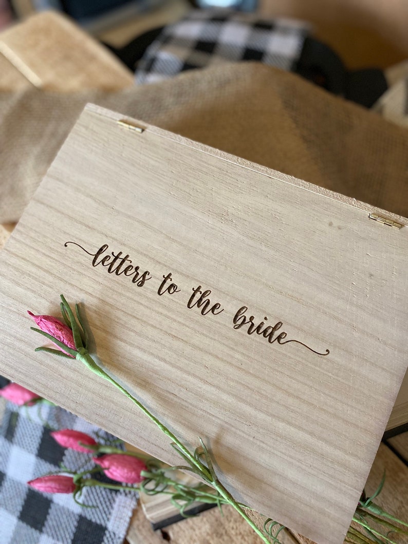 Puede incluir: Una caja de madera con tapa con bisagras, la tapa est&aacute; grabada con las palabras "cartas para la novia".