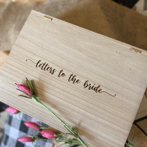 Puede incluir: Una caja de madera con las palabras "letters to the bride" grabadas en la tapa. La caja est&aacute; decorada con una flor rosa.