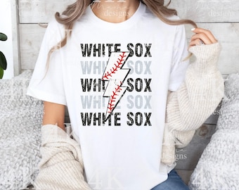 Op de afbeelding: Wit T-shirt met de tekst "WHITE SOX" in een gestapeld ontwerp en een honkbal-thema bliksemflits grafisch. De afbeelding is in zwart, wit en rood. Het shirt is wit.