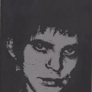 May include: A black and white portrait of a person with short, dark hair. The person is looking directly at the viewer with a serious expression.