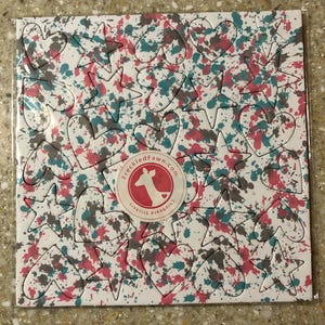 Puede incluir: Una hoja de pegatinas con forma de corazón y estrella con fondo blanco y diseño salpicado colorido en rosa, turquesa y gris. Las pegatinas son de cartón y son de freckledfawn.com.