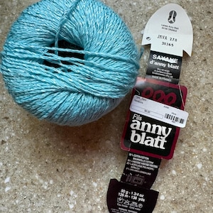 May include: A ball of bright turquoise yarn with a sheen, accompanied by a paper label featuring the text Anny Blatt, Java 278, 31365, 50 g - 1 3/4 oz, 126 m - 138 yds, and composition details including 35% cotton, 34% viscose, 23% acrylic, and 8% linen.