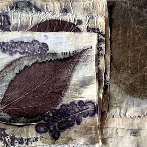 May include: Handmade fabric squares with botanical prints. The natural-toned fabric features dark brown and purple leaf imprints, creating a rustic aesthetic. The edges are frayed, adding to the handmade charm. The fabric is in a natural tone.