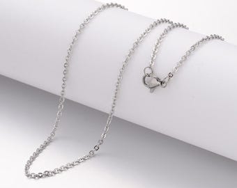 May include: A silver-colored necklace with a delicate chain design. The necklace features a simple, elegant style with a small clasp. The chain is made of small, round links.