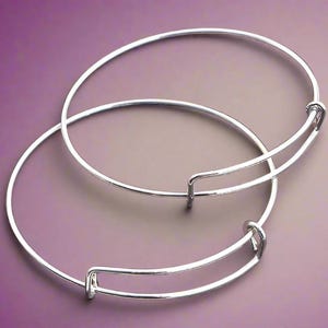 May include: Two silver bangle bracelets with a spring clasp closure.