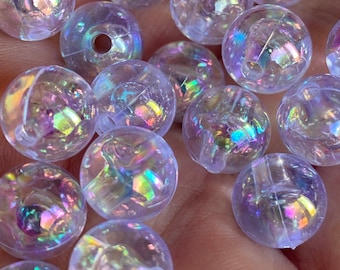 May include: A close-up of iridescent clear plastic beads. The beads are round and have a holographic finish. They are scattered on a hand.