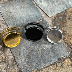 May include: Three adjustable ring blanks with round, flat, metal bases. The bases are gold, black, and silver.