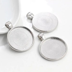 May include: Three silver-toned circular pendant trays with a smooth, raised outer rim and a textured, geometric pattern on the interior base. Each pendant features a small, integrated bail at the top for attachment to a chain or cord.