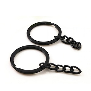 May include: Two black key rings with attached chain links. The key rings are round and have a matte finish. The chain links are also black and connect to the key rings. The background is white.