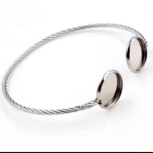 May include: A silver cable chain bracelet with two round, silver-toned, bezel settings for adding a cameo or other embellishment.