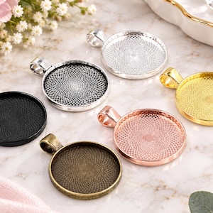 May include: A collection of six circular metal pendant trays featuring a textured, geometric lattice pattern on the interior base. The set includes finishes in matte black, silver, gold, rose gold, and antique bronze, each with a top bail loop.