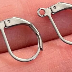 May include: Two silver-toned earring hooks with a lever back closure. The hooks are made of metal and have a smooth finish.